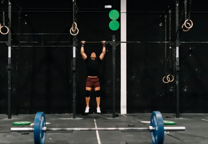 Mężczyzna wykonuje podciąganie na drążku w siłowni CrossFit.