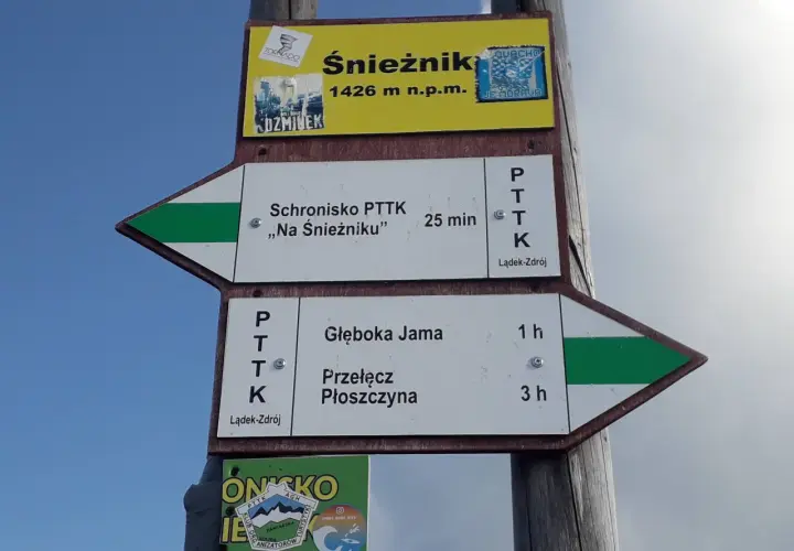 Znaki szlakowe na masywie Śnieżnika wskazują drogę do schroniska i na przełęcz.