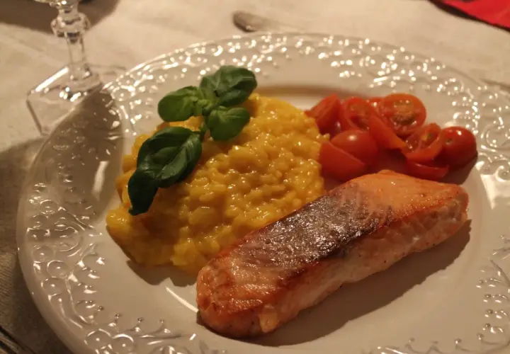 En härlig saffransrisotto med lax, garnerad med basilika och serverad med körsbärstomater. En festlig rätt!