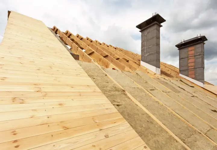 Struttura del tetto in legno con isolamento termico del tetto in lana minerale e due camini in costruzione.