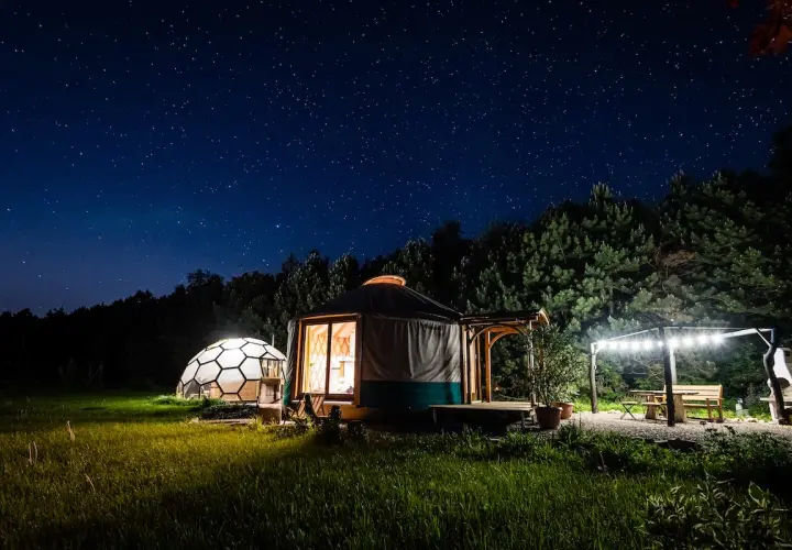 Nocne niebo pełne gwiazd nad jurtą i kopułą. Idealne klimatyczne miejsca na weekend we dwoje, z oświetlonym tarasem i grillem.