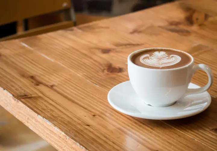 Biała filiżanka z kawą flat white, ozdobiona latte art. Dowiedz się, jak zrobić flat white w domu.