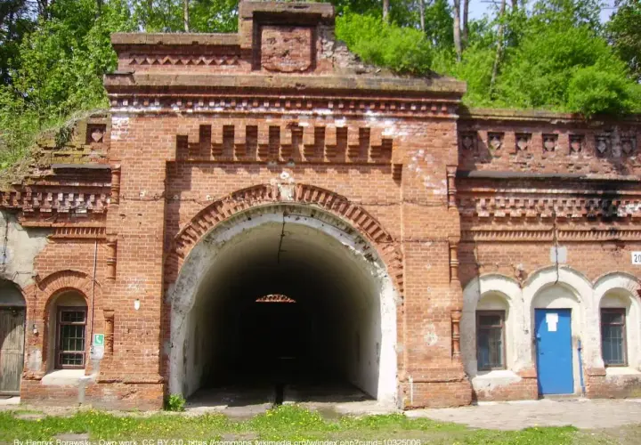 Wejście do tunelu w ceglanej twierdzy Osowiec. Zarośnięte zielenią mury i łukowate przejście.