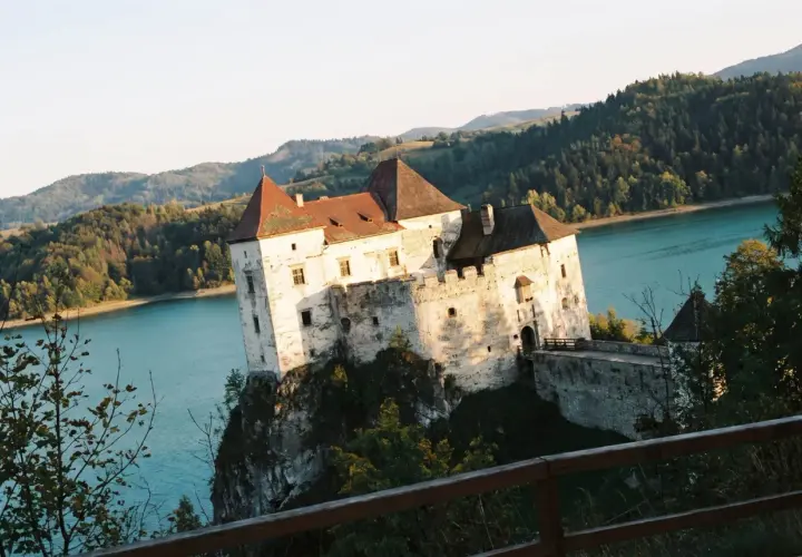 Niedzica-zamek trasa: malowniczy zamek na skale nad turkusową wodą, otoczony zielonymi wzgórzami.
