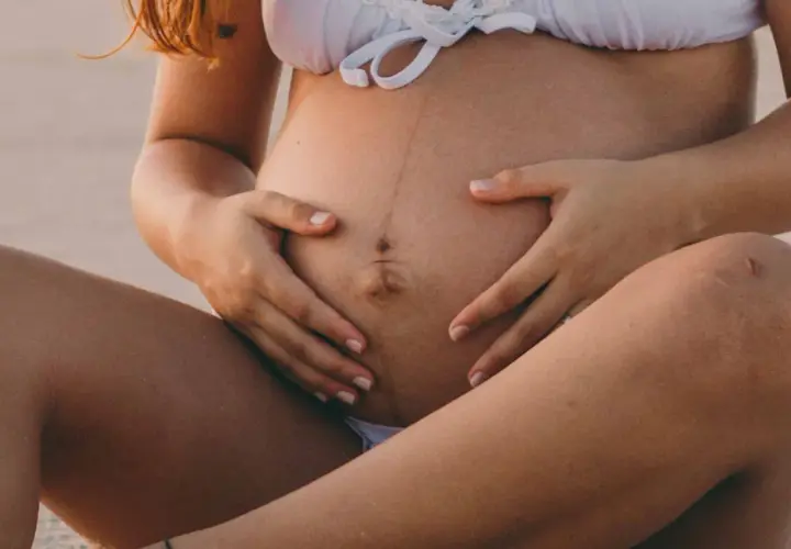 Ventre de femme enceinte avec une ligne brune visible, signe de grossesse. La ligne brune grossesse quel mois est souvent plus marquée vers le 5ème mois.