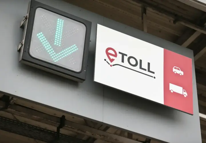 Zielony znak ze strzałkami w dół i logo e-TOLL. Informuje, jak zapłacić za autostradę, wskazując drogę dla samochodów i ciężarówek.
