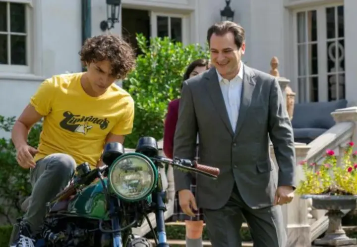 Un ragazzo su una moto e un uomo in giacca e cravatta sorridono. Le recensioni di "Your Honor" potrebbero descrivere questa scena.