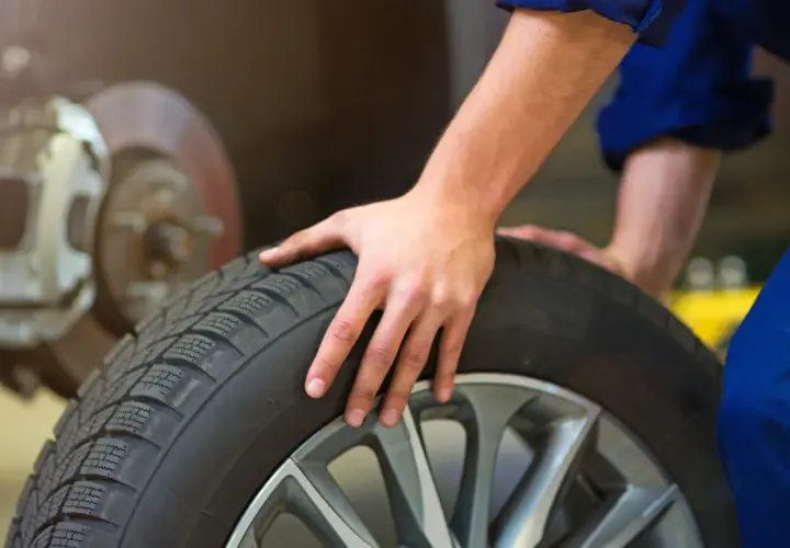 Mecánico revisa un neumático, pensando cuánto duran las ruedas de un coche.