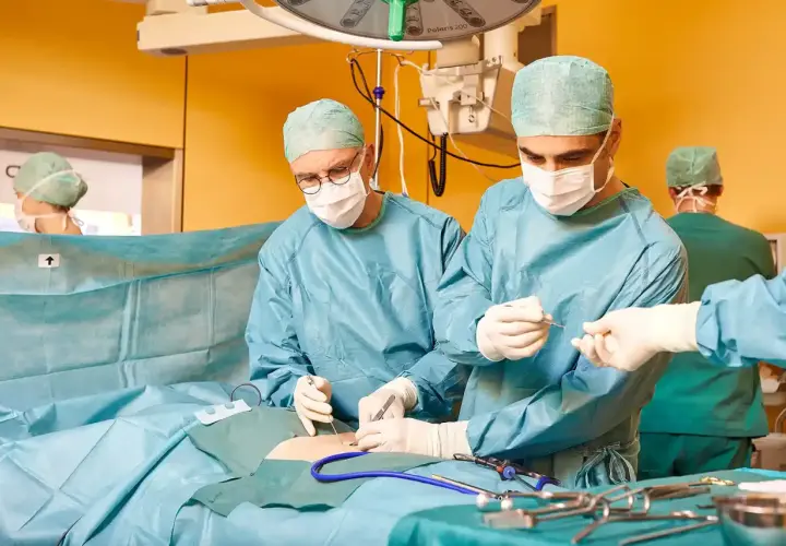 Chirurgen führen eine Hernien-OP mit Netz durch. Ein Team arbeitet konzentriert, um Komplikationen zu vermeiden.