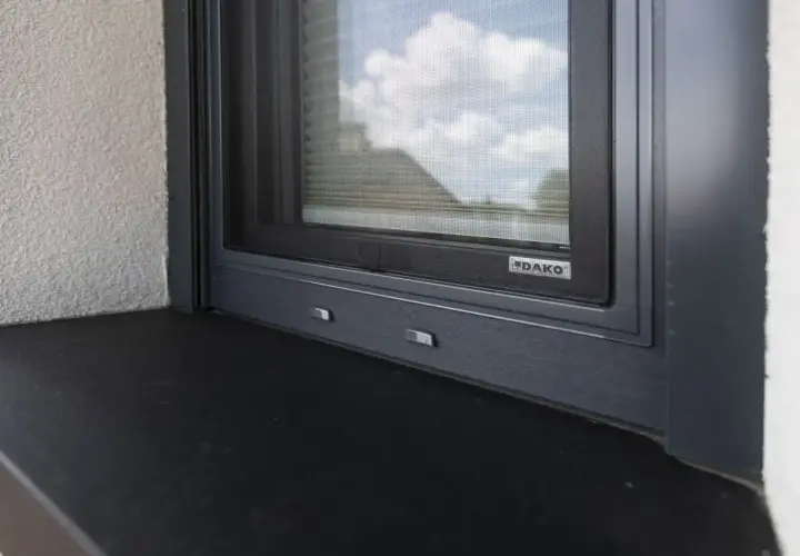Szary parapet zewnętrzny pod oknem z moskitierą. Zastanawiasz się, czym przykleić parapet zewnętrzny blaszany?