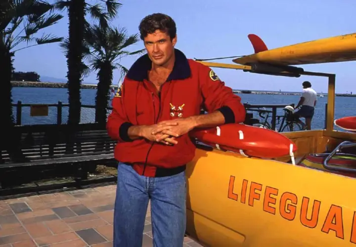 David Hasselhoff, ikona serialu Baywatch Słoneczny Patrol, pozuje przy łodzi ratowniczej.