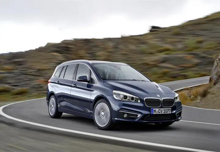 Un BMW Serie 2 Gran Tourer azul oscuro en una carretera sinuosa. A pesar de su diseño, algunos propietarios han reportado problemas.