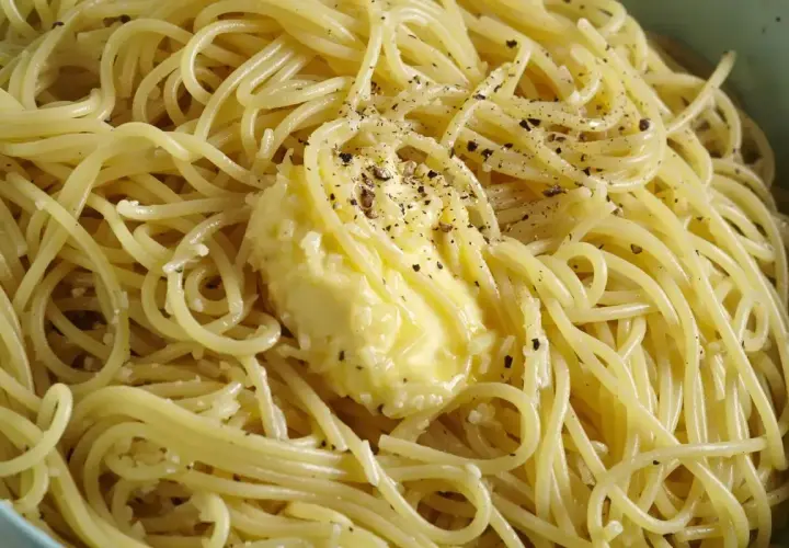 Spaghetti fumanti con burro fuso e pepe nero macinato, pronti per la cacio e pepe ricetta originale romana.