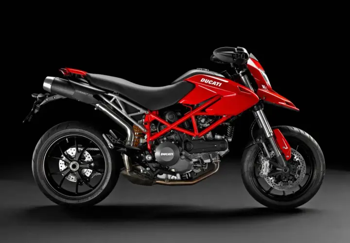 Czerwony Ducati Hypermotard 796 z czarnymi felgami i wydechem, gotowy do jazdy po miejskich ulicach.