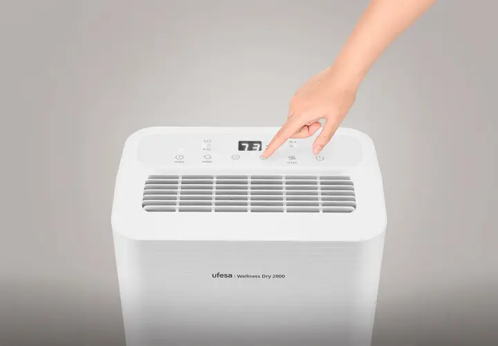 Mano ajustando el control de un deshumidificador Ufesa Wellness Dry 2000. Este deshumidificador sirve para controlar la humedad del ambiente.