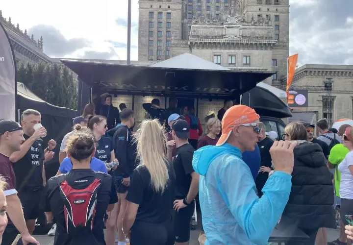 Grupa biegaczy przed budynkiem, dyskutują, czy można biegać codziennie. Na koszulkach napis "Run your way".