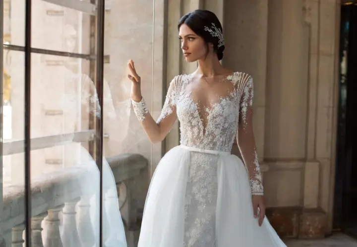 Elegancka panna młoda w sukni z koronki i tiulu, z ozdobną biżuterią we włosach. Inspiracja dla fryzur na ślub.
