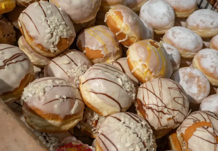 Pączki z lukrem i posypką, niektóre z polewą czekoladową. Czy paczki można mrozic? Tak, można je zamrozić, by cieszyć się nimi dłużej.