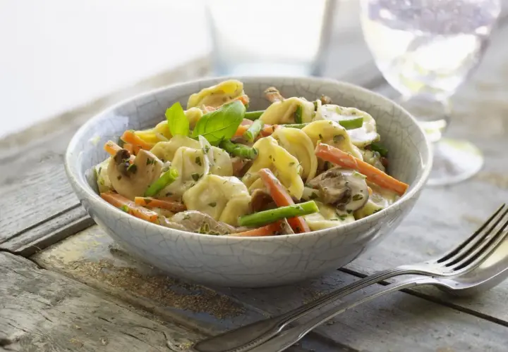 Tortellini con champiñones, zanahoria y espárragos en una cremosa salsa para pastel de verduras.