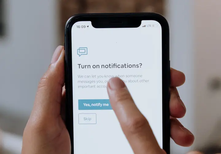 Palec dotyka ekranu telefonu, wybierając opcję "Yes, notify me" (Tak, powiadom mnie) na ekranie z pytaniem o włączenie powiadomień po polsku.