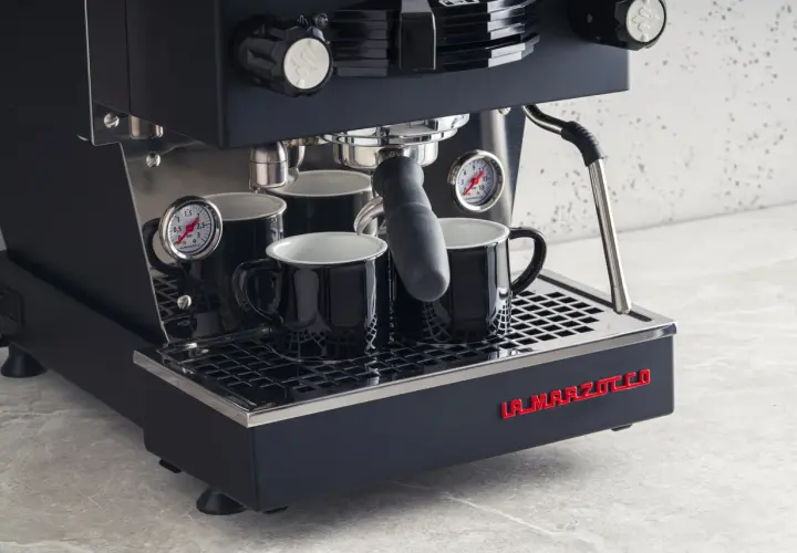 Profesjonalny ekspres do kawy La Marzocco z dwoma czarnymi filiżankami. Dowiedz się, jak odpowietrzyć ekspres Delonghi, by cieszyć się idealnym espresso.