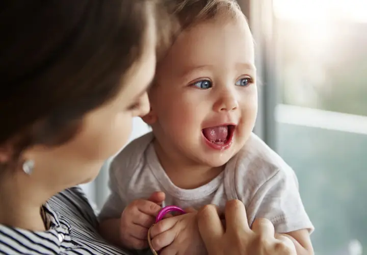 Bambino sorridente con la mamma, forse è l'inizio della lallazione.