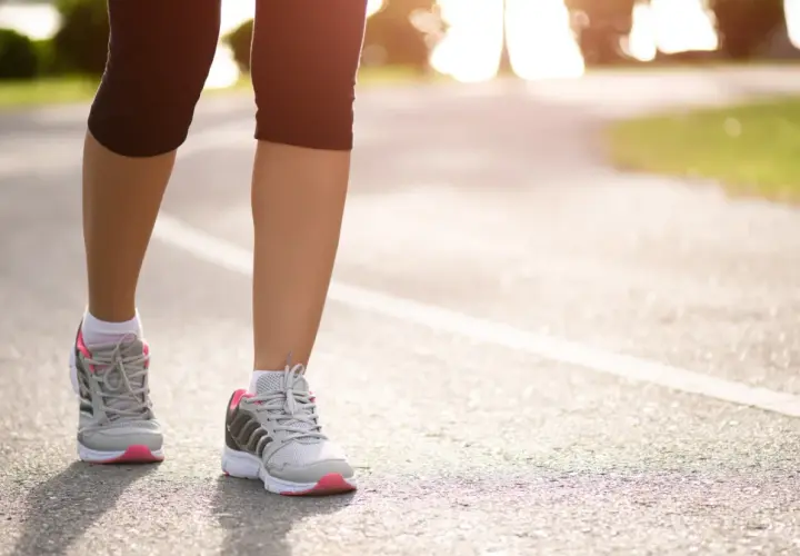 Kobieta w sportowych butach biegnie po asfalcie. Czy bieganie odchudza? Tak, regularny wysiłek fizyczny pomaga spalać kalorie i kształtować sylwetkę.