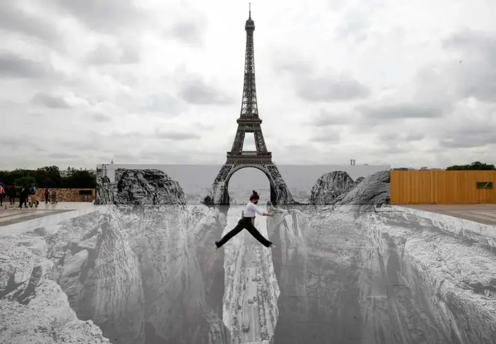 Une femme saute au-dessus d'un gouffre peint au sol, devant la Tour Eiffel. Un **tableau trompe l'oeil** saisissant.