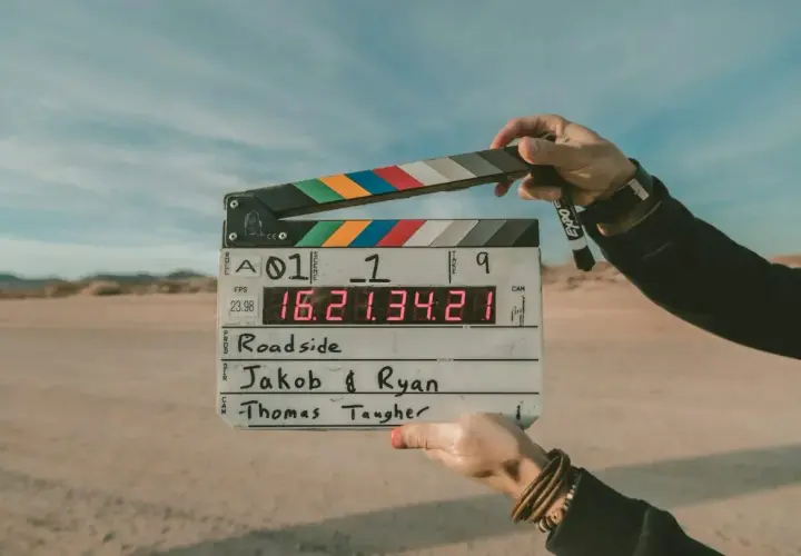 Pustynia, plan filmowy "Roadside". Dwie ręce trzymają klaps z napisem "Jakob & Ryan" i "Thomas Taugher". Opis miejsca.