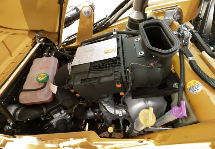 Silnik koparki Cat 428C z widocznym zbiornikiem płynu chłodniczego i wlewem oleju hydraulicznego.