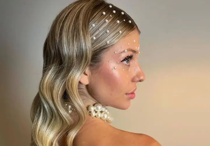 Peinados para salir de fiesta: melena rubia ondulada adornada con perlas en el cabello y rostro, look deslumbrante.