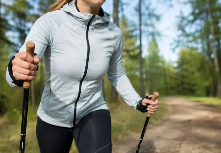 Kobieta z kijkami nordic walking w lesie. Dowiedz się, jak dobrać odpowiednie kijki do swojego wzrostu i stylu marszu.
