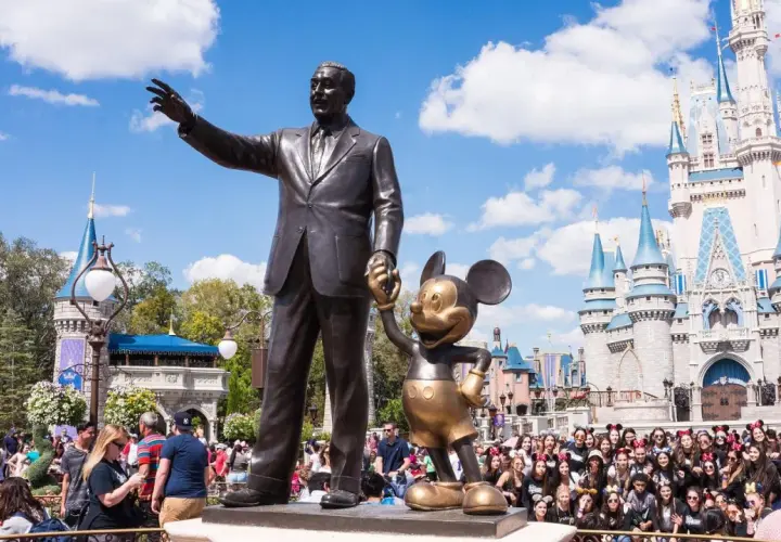 Walt Disney i Myszka Miki pozdrawiają tłumy przed zamkiem w największym Disneylandzie na świecie.