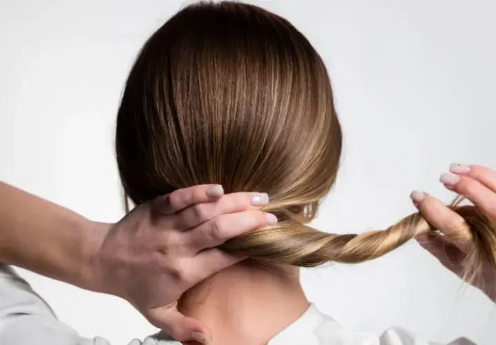 Manos trenzando el cabello para crear peinados para dormir, evitando enredos y luciendo un estilo cuidado al despertar.