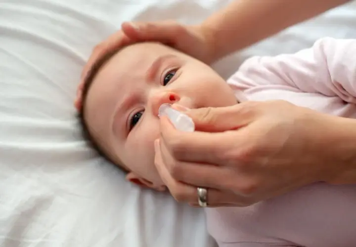 Mani che aiutano un neonato di 2 mesi con la tosse, somministrando gocce nasali per alleviare il naso chiuso.