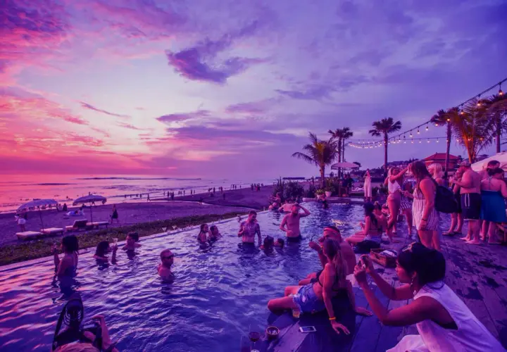 Imprezowa atmosfera nad morzem, ludzie kąpią się w basenie przy zachodzie słońca. Idealne miejsce dla szukających najbardziej imprezowych miast nad morzem.