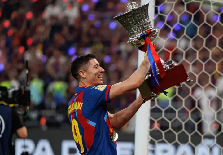 Robert Lewandowski z pucharem, symbol jego bogatej kariery. Krótka biografia tego piłkarza to historia sukcesów.