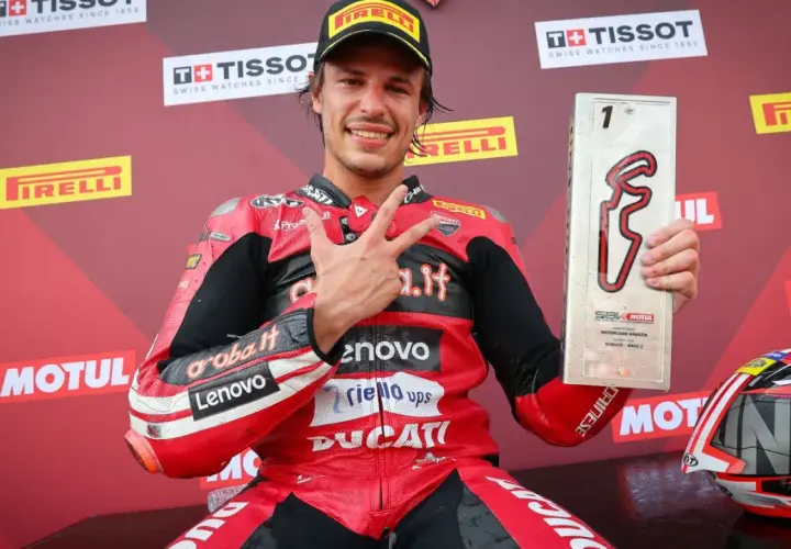 Nicolò Bulega, piloto de Ducati, celebra su victoria en Motorland Aragón con el trofeo y haciendo la señal de la victoria.