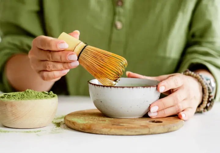 Przygotowanie najlepszej zielonej herbaty matcha. W drewnianej miseczce proszek, w ceramicznej miseczce napar, ubijany bambusowym miotełką.