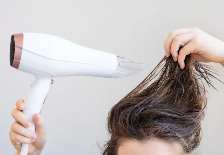 Secando el pelo mojado con un secador para dar volumen al pelo fino.