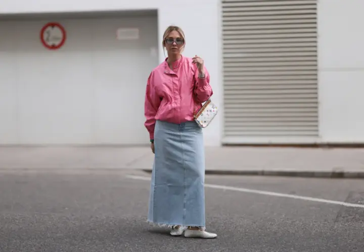 Modna stylizacja z jeansową spódnicą maxi i różową kurtką. Kobieta w okularach przeciwsłonecznych i torebce z kolorowym wzorem.