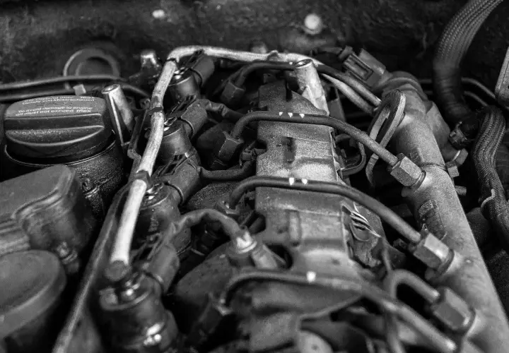 Silnik samochodowy, widok z góry. Widać przewody, wtryskiwacze i korek wlewu oleju z napisem "To avoid damage to engine oil must not exceed max". Może to oznaczać, że jest za dużo oleju w aucie.