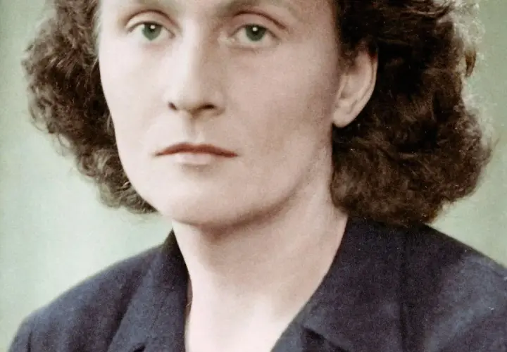 Portret Catherine Dior z zielonymi oczami i kręconymi włosami, w ciemnej marynarce.
