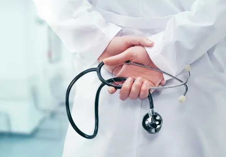 Mani di un medico con stetoscopio dietro la schiena, forse riflettendo su dimissioni dirigente medico e ferie non godute.