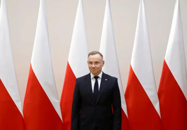 Prezydent Duda stoi przed polskimi flagami. Zastanawiamy się, dlaczego prezydent nie podpisał ustawy o mowie nienawiści przed marcem 2026.