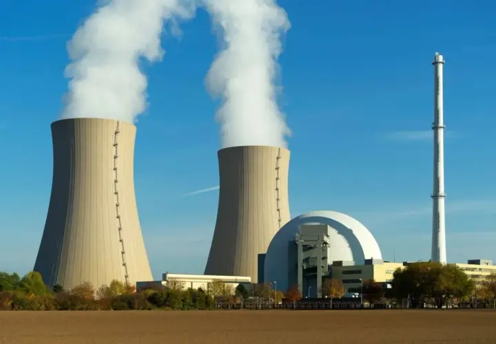 Dwie chłodnie kominowe elektrowni jądrowej z białym dymem na tle błękitnego nieba.