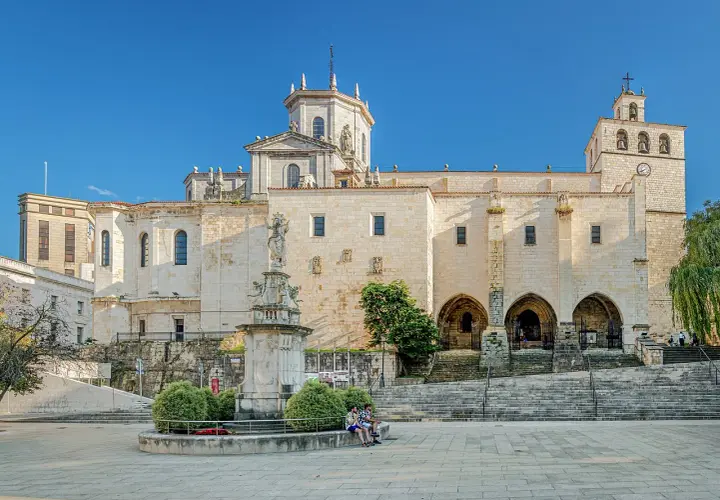 La imponente catedral de Santander se alza majestuosa bajo un cielo azul, con su fachada de piedra iluminada por el sol.