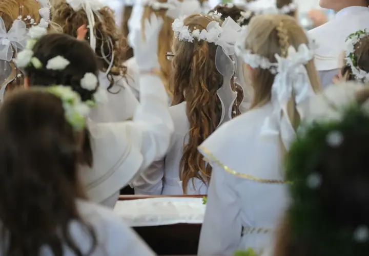 Dzieci w bieli, wianki na głowach, przygotowują się do komunii. Zastanawiasz się, ile daje chrzestny na komunię?