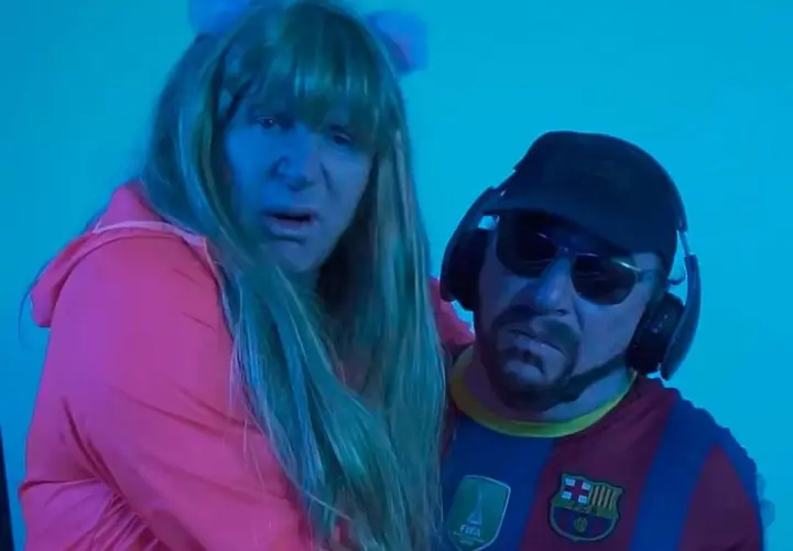 Dos personas con peluca y gorra, una con camiseta del Barça, parecen estar cantando la letra de "el pantalon".