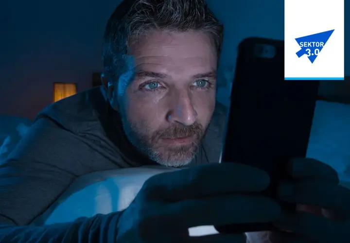 Mężczyzna wpatruje się w ekran telefonu w ciemności, jego oczy błyszczą. Czy to uzależnienie od muzyki, czy od mediów społecznościowych?